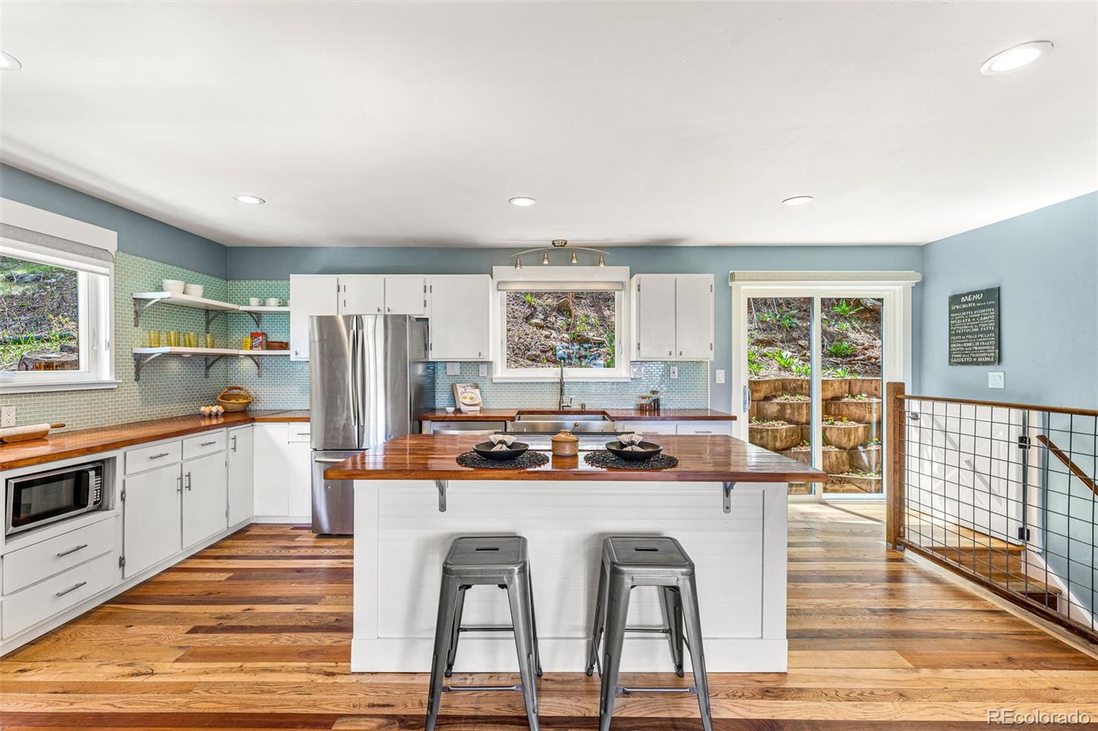 30242 Pine Crest Drive Evergreen, CO 80439 - Photo 4 of 28 a kitchen with stainless steel appliances granite countertop a stove and white cabinets with wooden floor