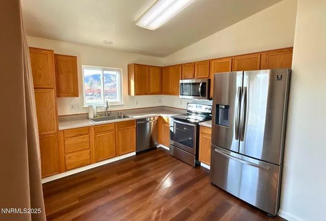 a kitchen with stainless steel appliances a refrigerator sink and wooden floor