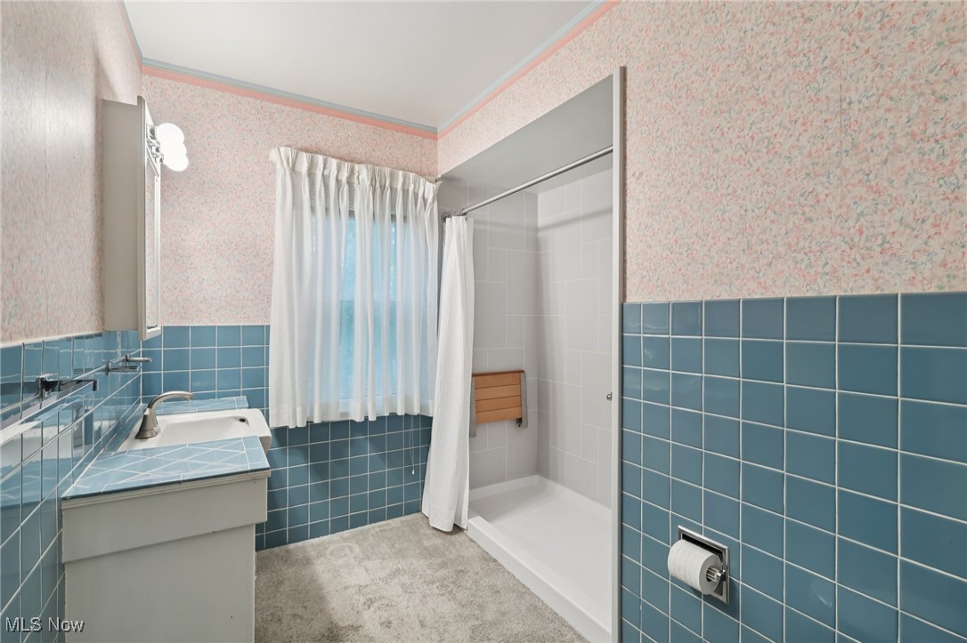 33300 South Woodland Road Cleveland, OH 44124 - Photo 34 of 50 Full bath with tile walls, wallpapered walls, a stall shower, vanity, and wainscoting