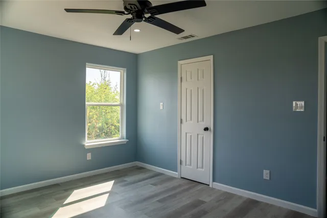 an empty room with a window and a fan
