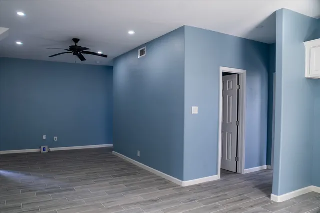 en empty room with wooden floor and a ceiling fan