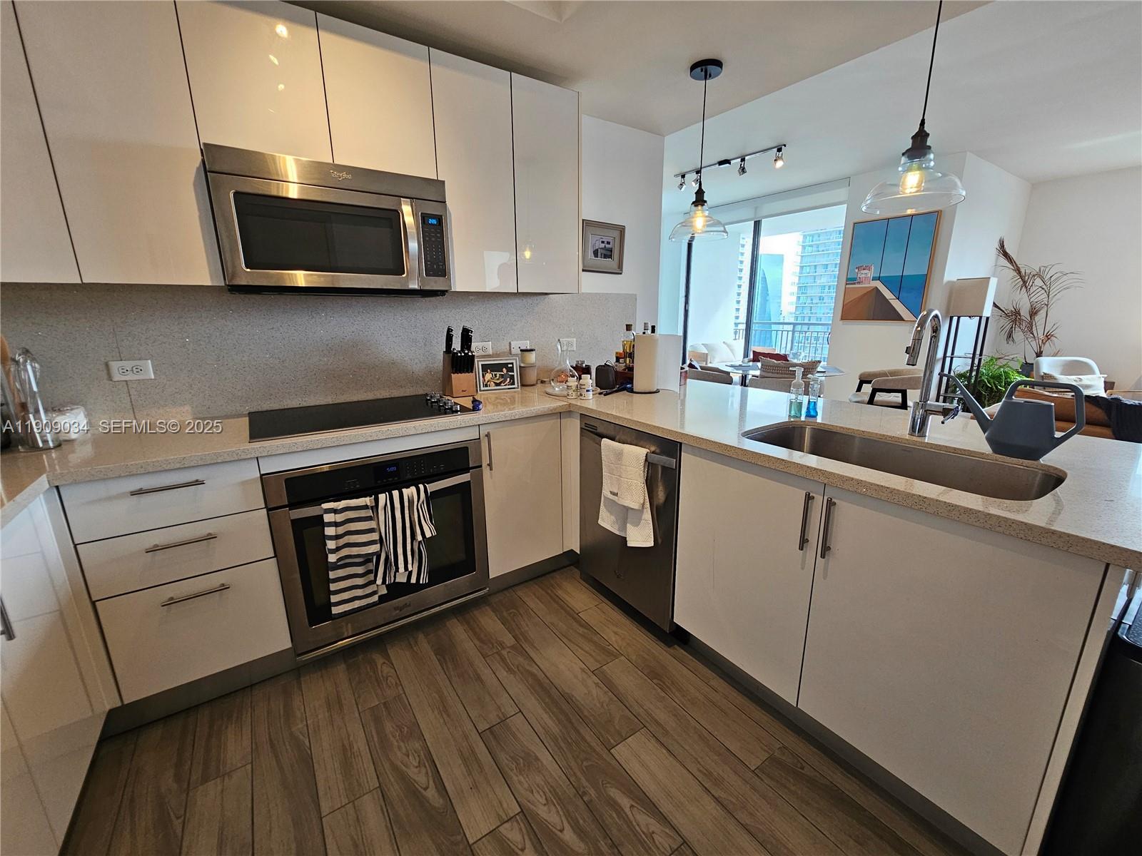 999 Southwest 1st Avenue, Unit 3004 Miami, FL 33130 - Photo 18 of 36 a kitchen with stainless steel appliances granite countertop a stove a sink dishwasher and a microwave oven with white cabinets