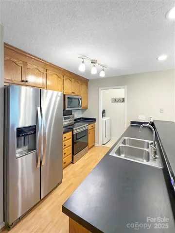 a kitchen with stainless steel appliances granite countertop a refrigerator a sink and a stove