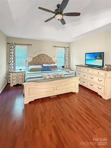 a spacious bedroom with a bed and a flat tv screen on dresser