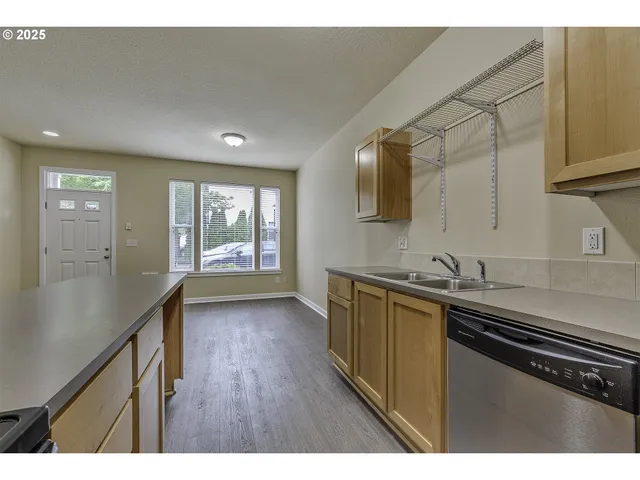 a kitchen with stainless steel appliances a sink dishwasher a stove a refrigerator and wooden floor