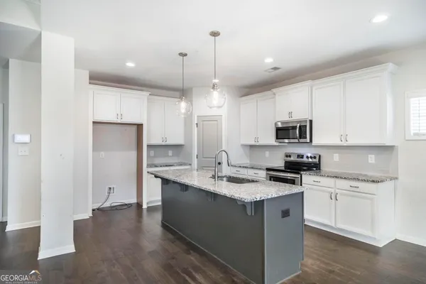 a kitchen with kitchen island granite countertop a sink a counter space appliances and cabinets