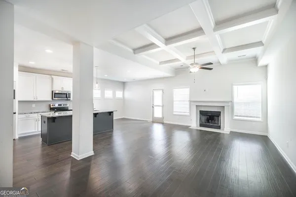 a view of an empty room and kitchen with a ceiling fan window