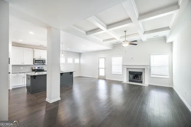 a view of an empty room and kitchen with a ceiling fan window
