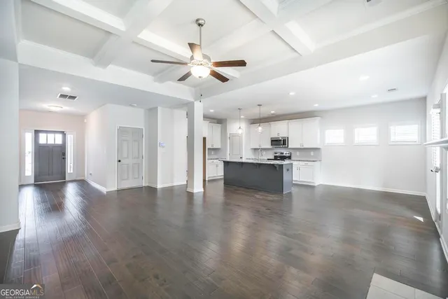 an empty room with wooden floor and a ceiling fan