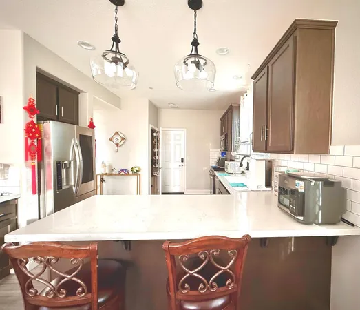 a large kitchen with stainless steel appliances kitchen island granite countertop a sink and a refrigerator