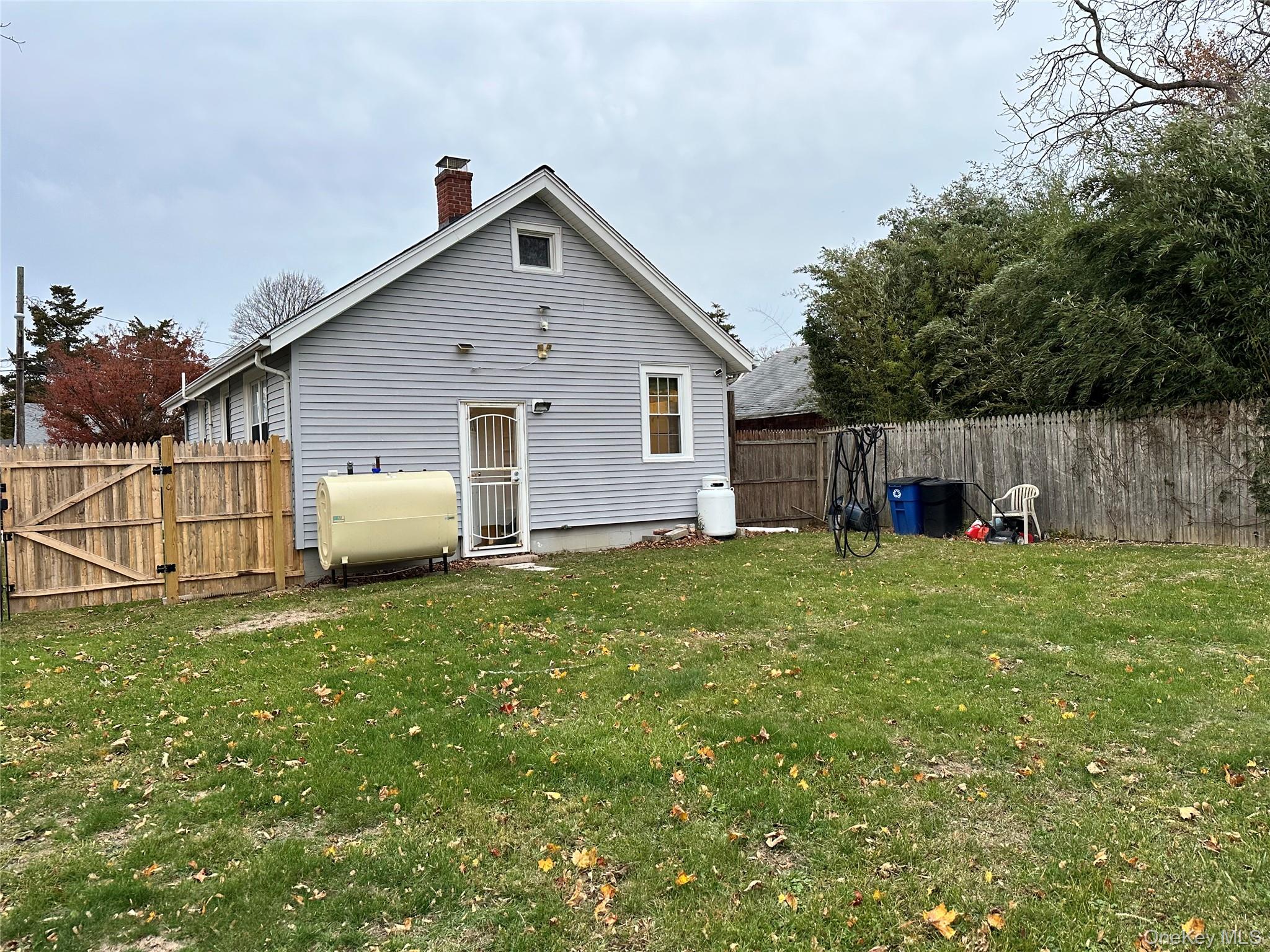 517 Flint Street Greenport, NY 11944 - Photo 19 of 20 Back of house featuring a gate, oil tank, a fully fenced backyard, and a chimney.