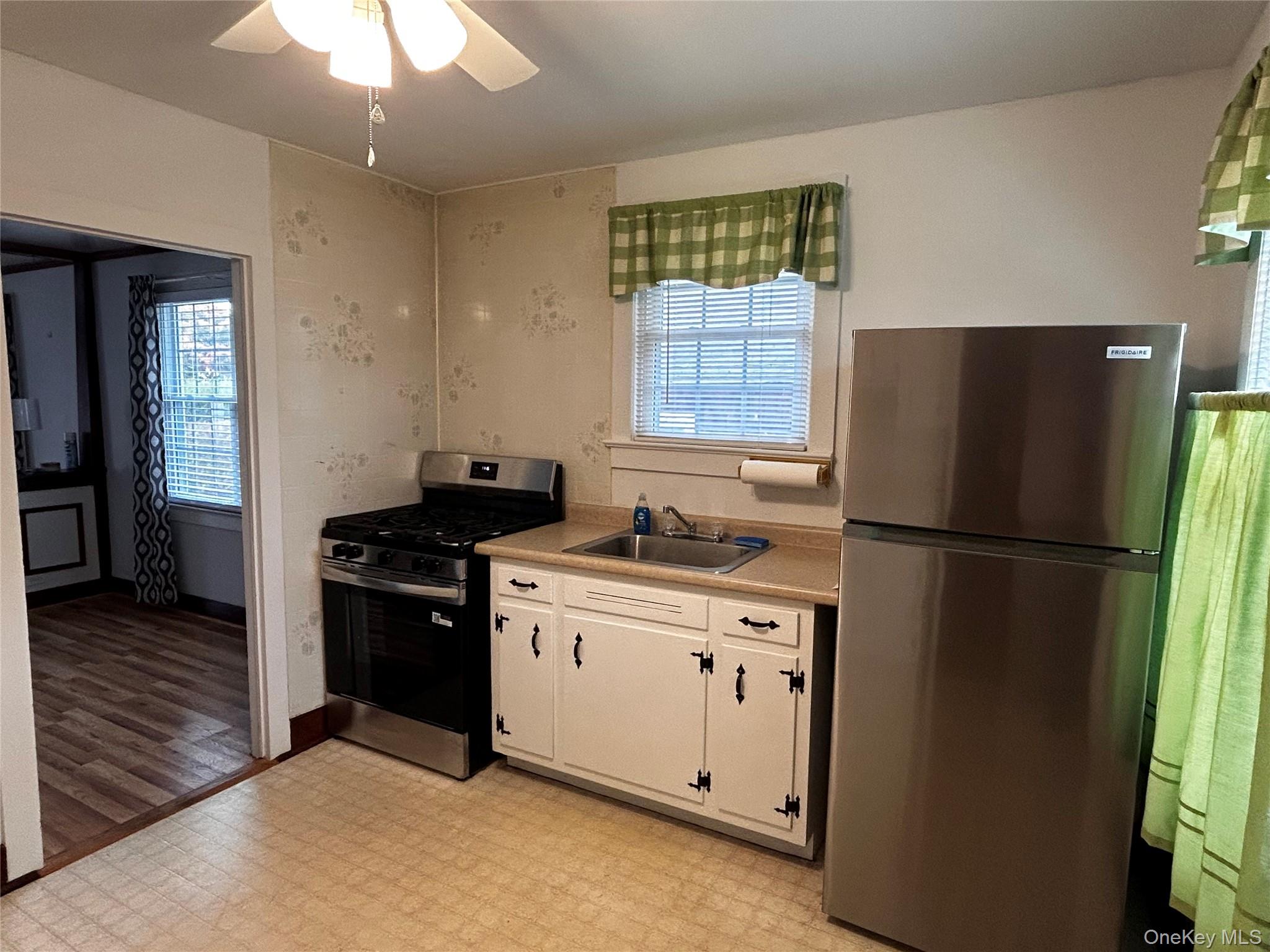 517 Flint Street Greenport, NY 11944 - Photo 9 of 20 Kitchen with new appliances with stainless steel finishes, light flooring, light countertops, ceiling fan, and white cabinetry