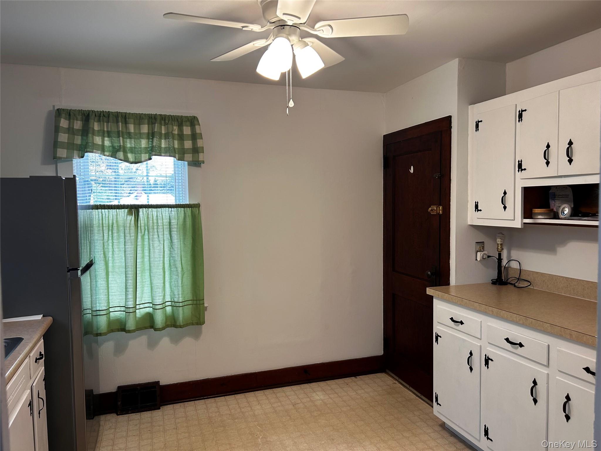 517 Flint Street Greenport, NY 11944 - Photo 10 of 20 Kitchen with white cabinets, new freestanding stainless steel refrigerator, light countertops, and light floors