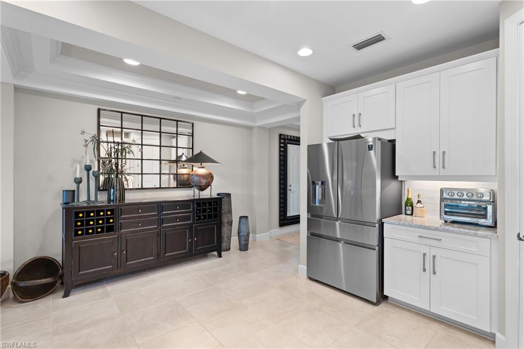9646 Montelanico Loop, Unit 102 Naples, FL 34119 - Photo 11 of 42 a kitchen with granite countertop a refrigerator and a stove top oven