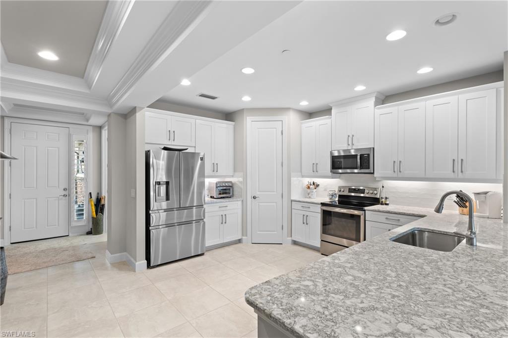 9646 Montelanico Loop, Unit 102 Naples, FL 34119 - Photo 8 of 42 a kitchen with stainless steel appliances granite countertop a refrigerator sink and stove