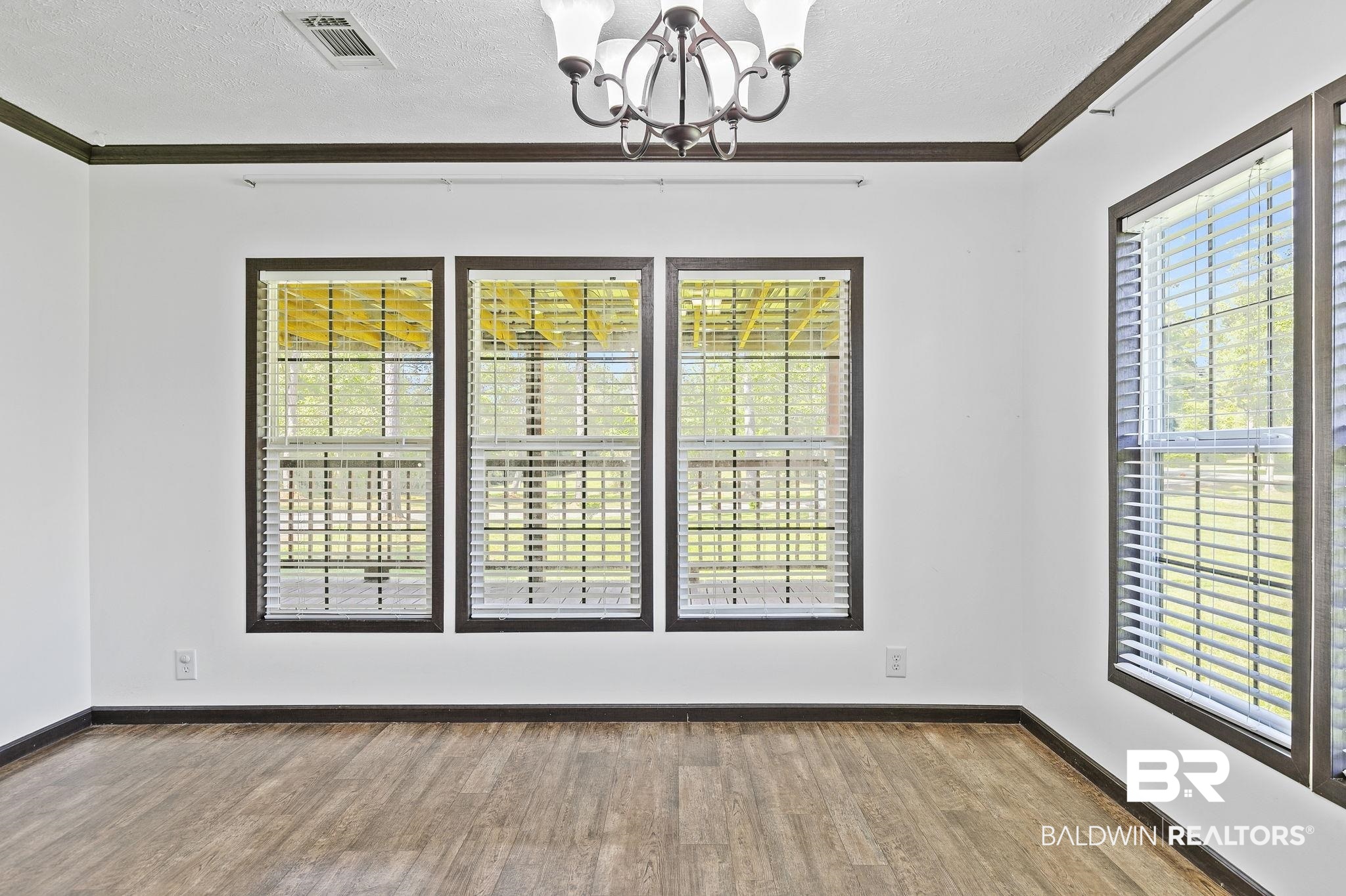 35641 County Road 39 Stapleton, AL 36578 - Photo 17 of 46 Spare room featuring a notable chandelier, crown molding, hardwood / wood-style floors, and a textured ceiling