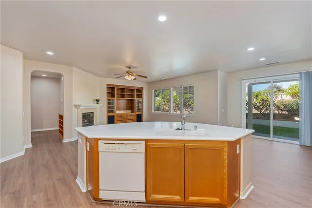 a dining hall with stainless steel appliances granite countertop a sink a microwave refrigerator and a dining table with wooden floor