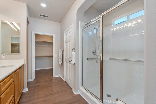 a bathroom with a glass shower door a sink and a mirror