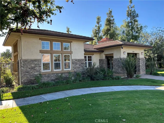 a view of a house with a yard plants and large tree