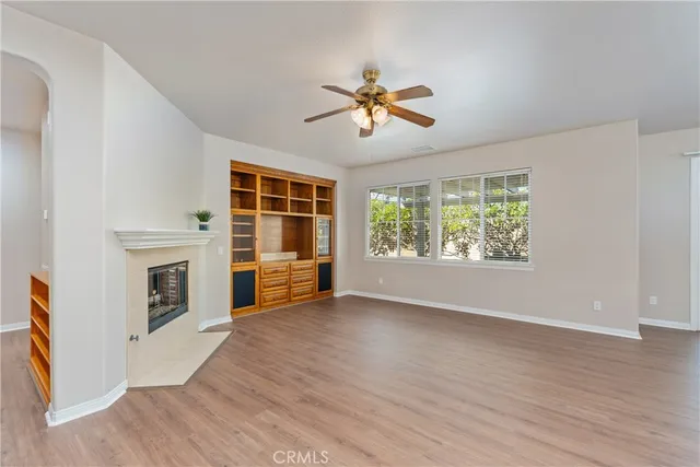 a view of a livingroom with a fireplace a ceiling fan and wooden floor