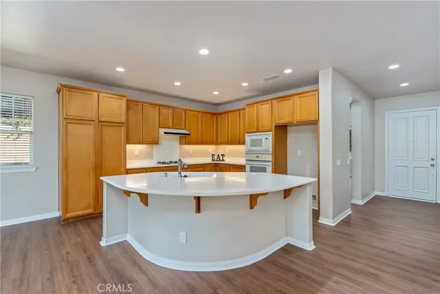 a view of a kitchen with stainless steel appliances granite countertop a sink a stove and a wooden floors