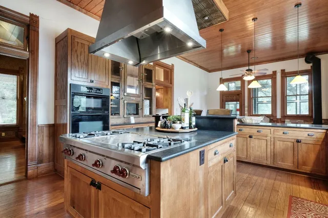 a kitchen with stainless steel appliances granite countertop a stove and a view of living room