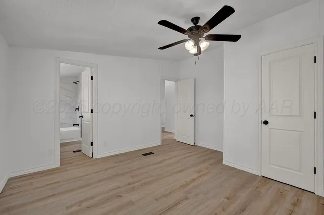 an empty room with wooden floor and ceiling fan