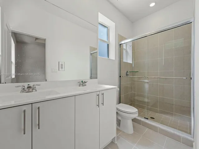 a bathroom with a double vanity sink toilet and shower