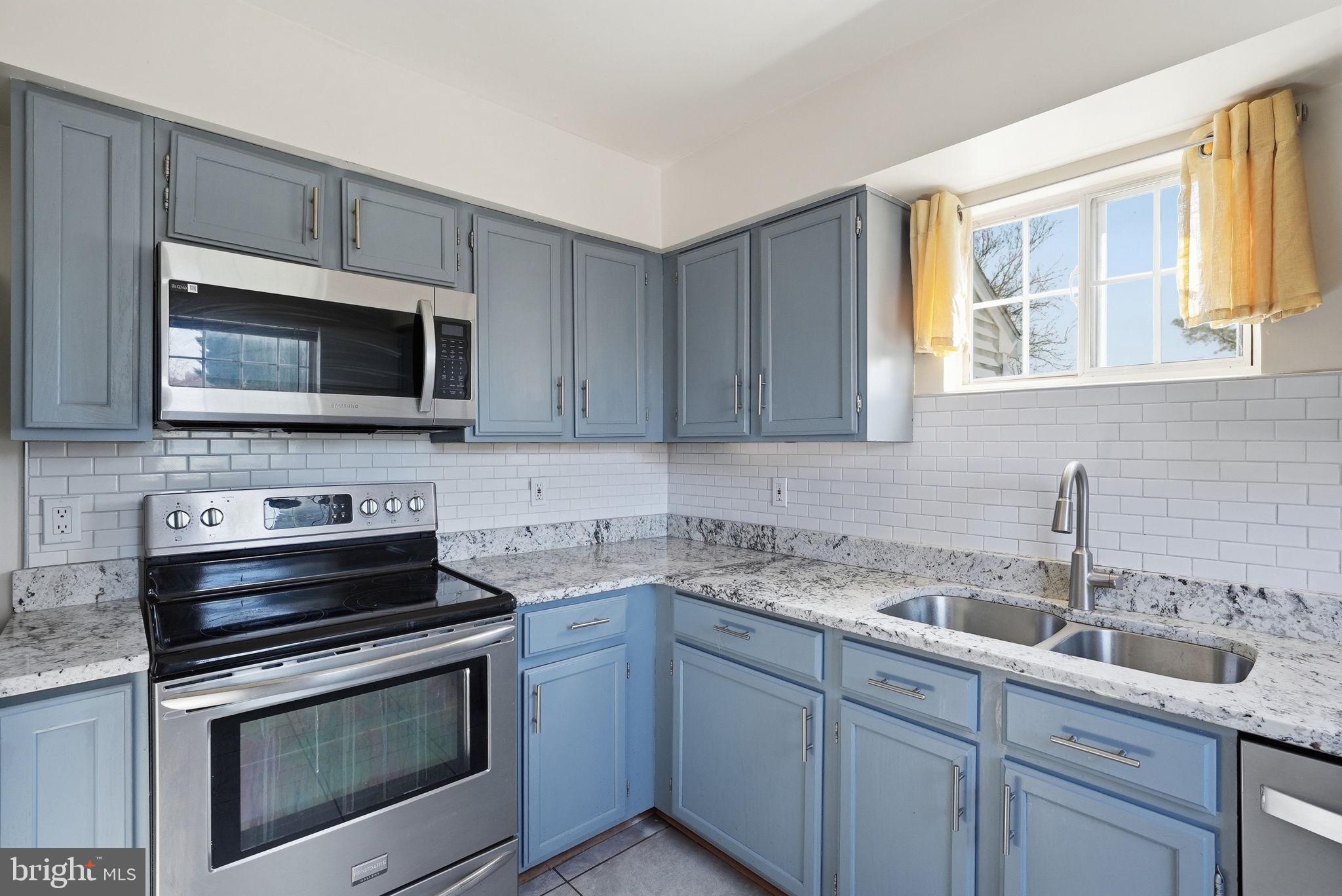 1003 Spring Valley Court Fort Washington, MD 20744 - Photo 10 of 25 a kitchen with sink a microwave a stove and cabinets