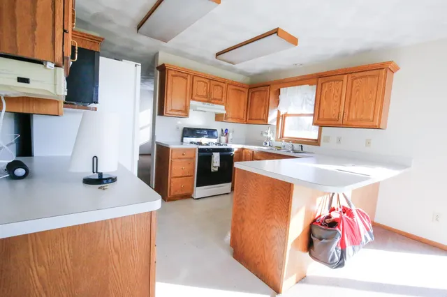 a kitchen with stainless steel appliances granite countertop a sink dishwasher stove top oven and cabinets with wooden floor