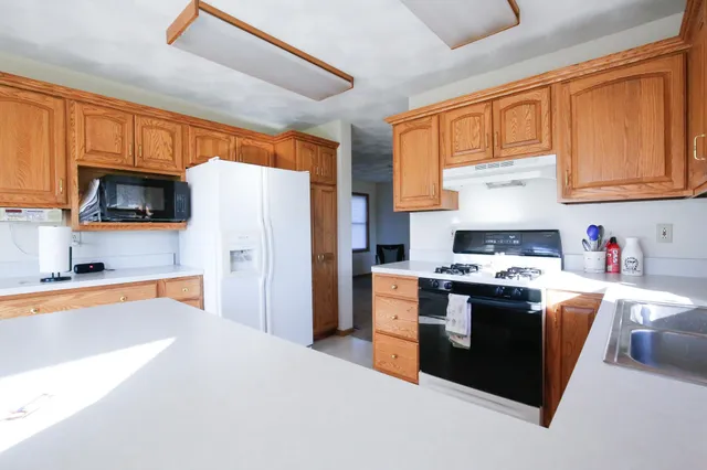 a kitchen with stainless steel appliances stove top oven refrigerator and a window