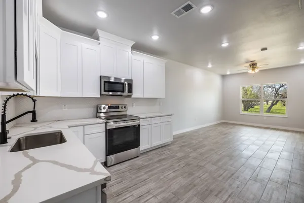 a kitchen with stainless steel appliances granite countertop a stove a sink and a microwave