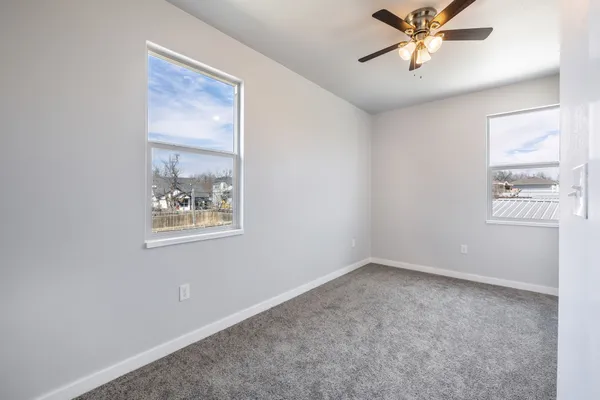 an empty room with windows and fan