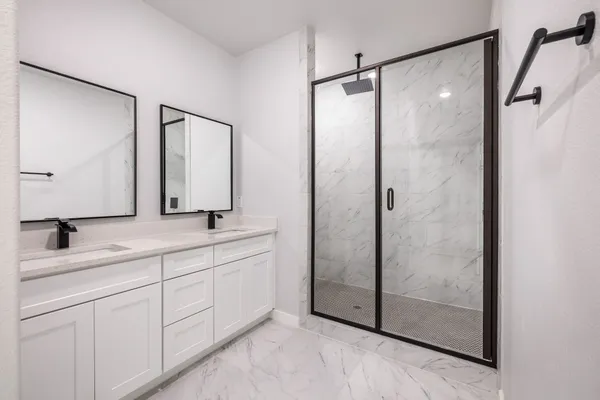 a bathroom with a double vanity sink mirror and shower