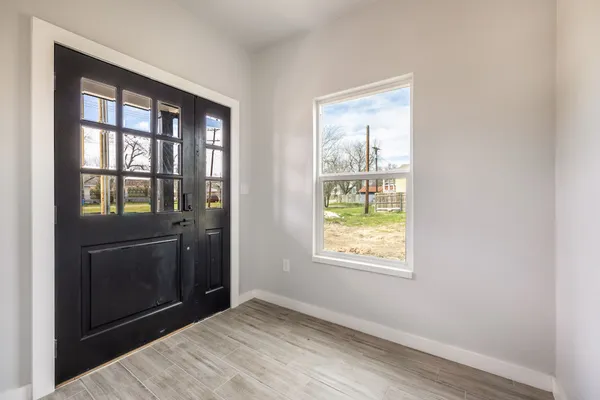 a view of an empty room with wooden floor and a window