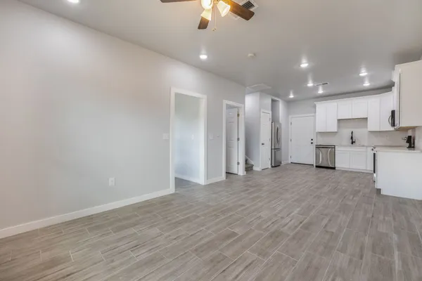 a view of a kitchen with a refrigerator a ceiling fan and wooden floor