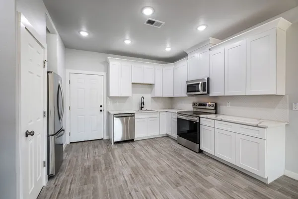 a kitchen with cabinets wooden floor and stainless steel appliances