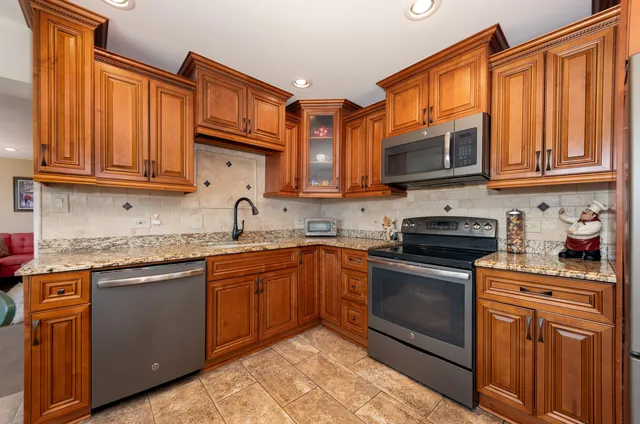a kitchen with stainless steel appliances granite countertop a sink dishwasher stove and cabinets with wooden floor