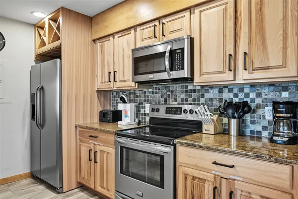 a kitchen with stainless steel appliances granite countertop a stove a microwave and a refrigerator