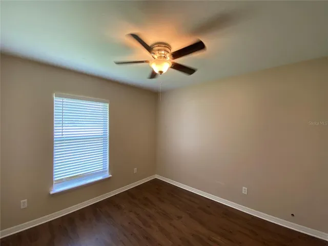 a view of a room with wooden floor and a ceiling fan