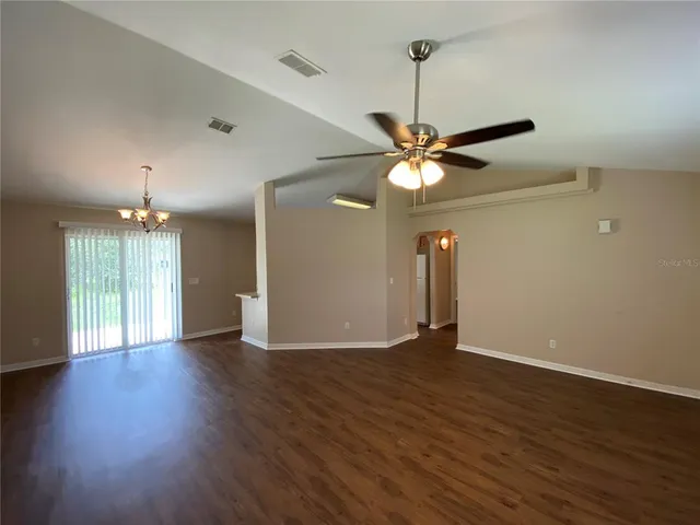 a view of an empty room with wooden floor and a ceiling fan