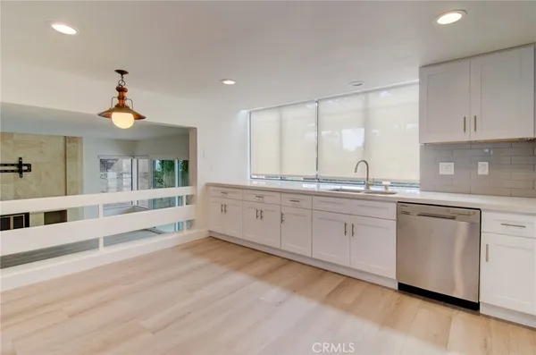 a large white kitchen with granite countertop a sink a window and stainless steel appliances