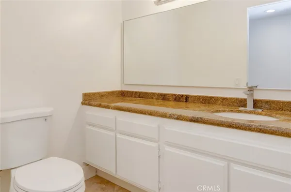 a bathroom with a granite countertop toilet and a sink