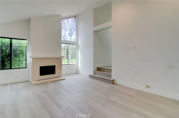 an empty room with wooden floor a fireplace and windows