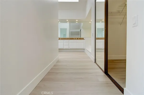 a view of a hallway with wooden floor and a large mirror