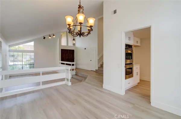 a view of a livingroom with wooden floor a ceiling fan and windows
