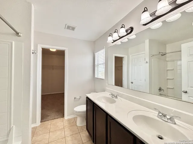 a bathroom with a sink a toilet a mirror and shower