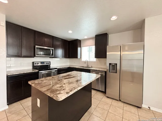 a kitchen with a sink a microwave a refrigerator and black cabinets