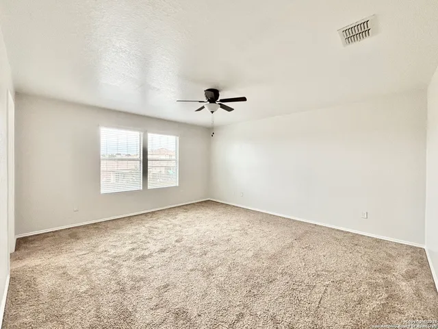 an empty room with a window and a ceiling fan