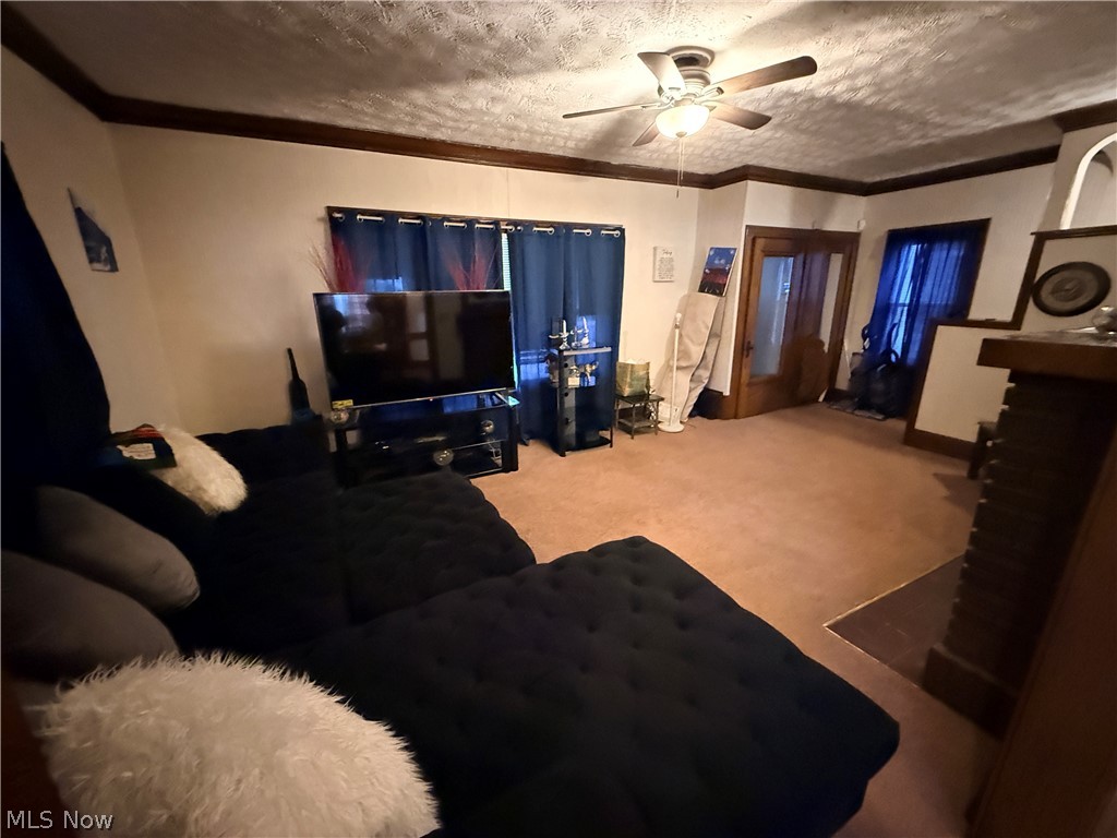 980 Brunswick Road Cleveland Heights, OH 44112 - Photo 5 of 11 Living room featuring light carpet, a ceiling fan, a fireplace, a textured ceiling, and ornamental molding